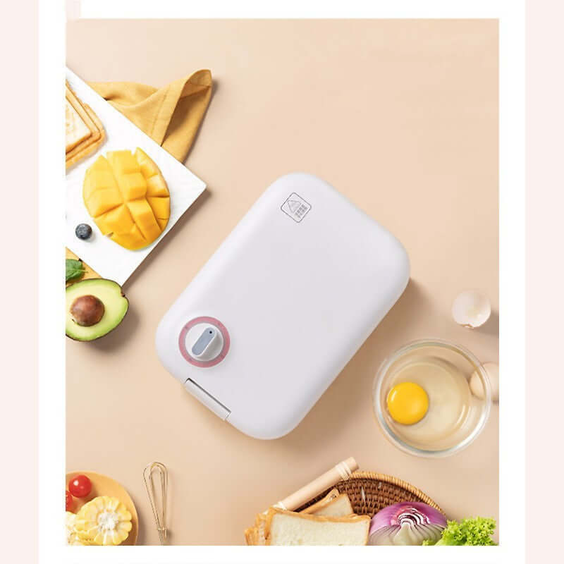White kitchen appliance on beige table with avocado, mango, egg, bread, onion, and utensils