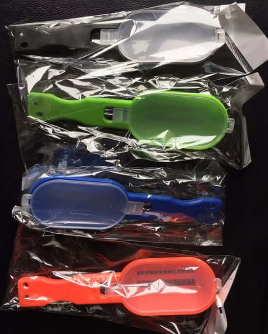 Set of four plastic vegetable peelers in different colors, individually packed in plastic.
