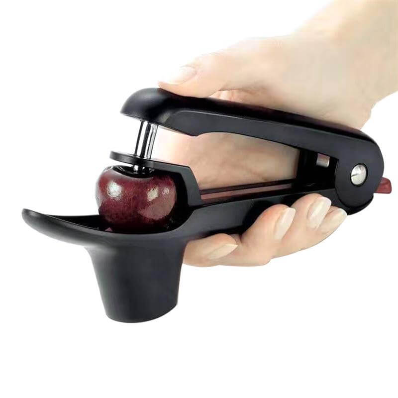 Hand using black cherry pitter kitchen tool to remove cherry pit