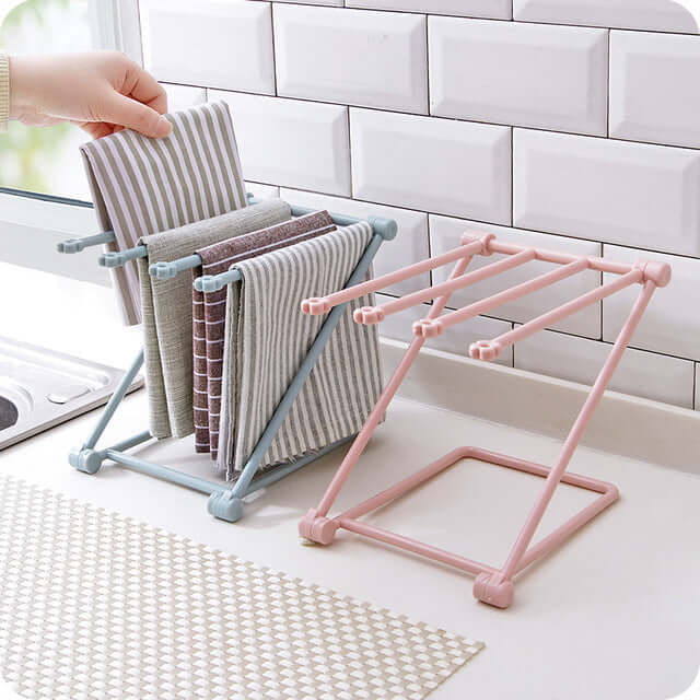 Kitchen countertop towel racks with colorful dish towels and a hand placing one towel