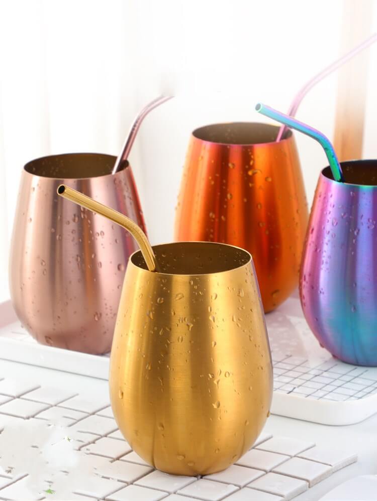Set of colorful stainless steel tumblers with matching straws and water droplets on surface