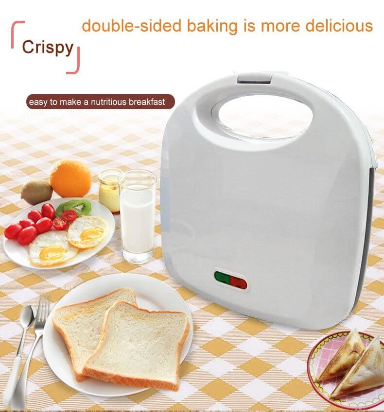 Double-sided sandwich maker on a kitchen table with toast, eggs, fruit, and milk.