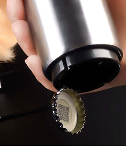 Stainless steel bottle opener removing a metal cap from a glass bottle