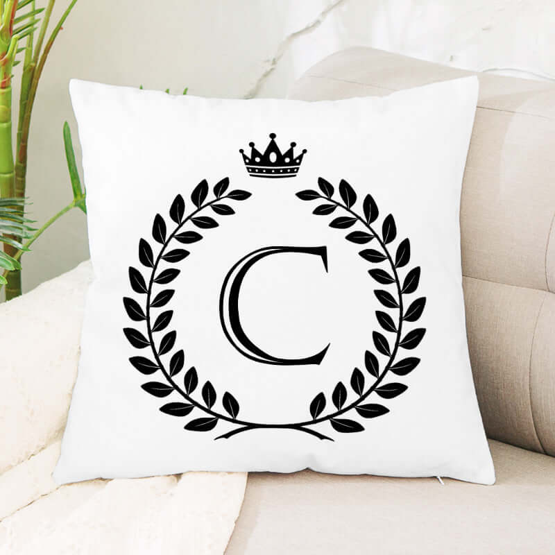 White decorative throw pillow with black monogram C, laurel wreath, and crown design