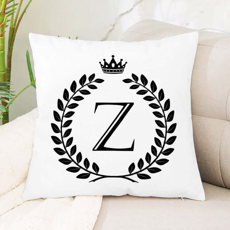 White decorative throw pillow with black letter Z, laurel wreath, and crown design on a sofa