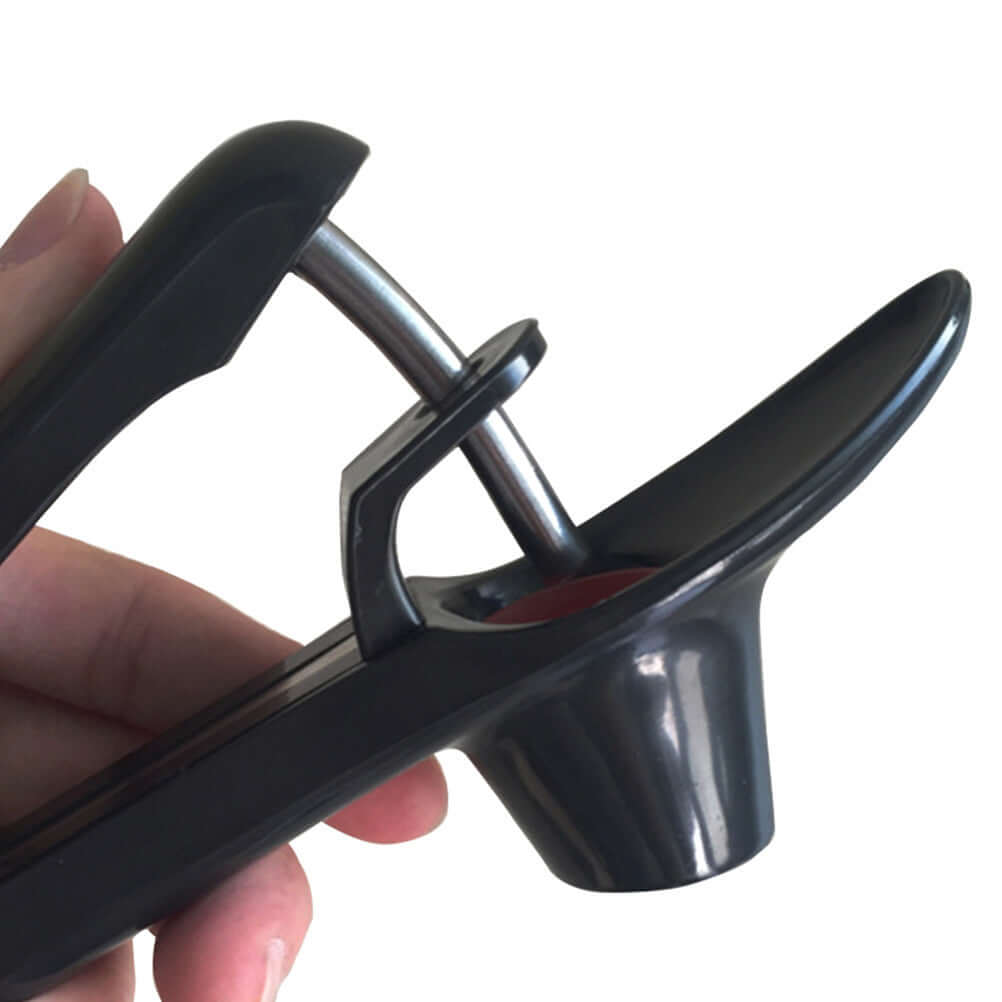 Hand holding a black cherry pitter kitchen tool with stainless steel mechanism