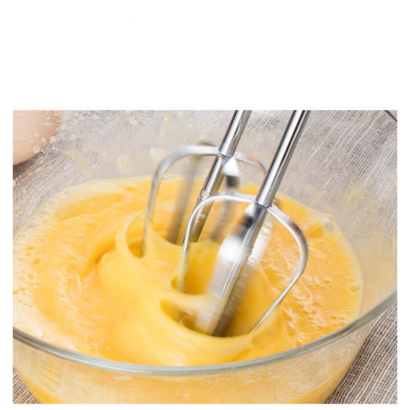 Electric hand mixer whipping eggs in a glass bowl for baking or kitchen preparation