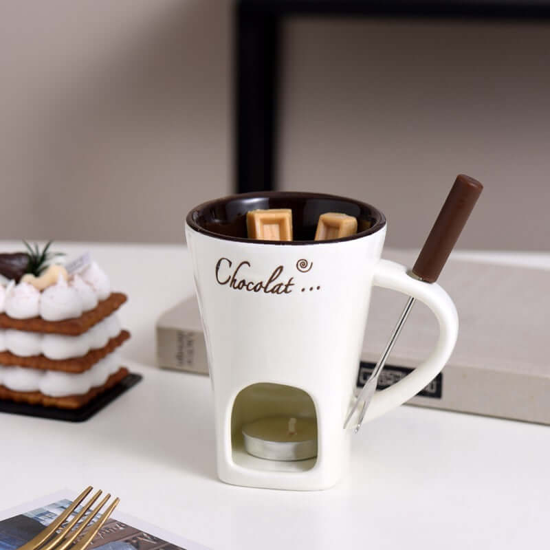 Ceramic chocolate fondue mug with tealight, melting chocolate, fondue fork, and dessert.