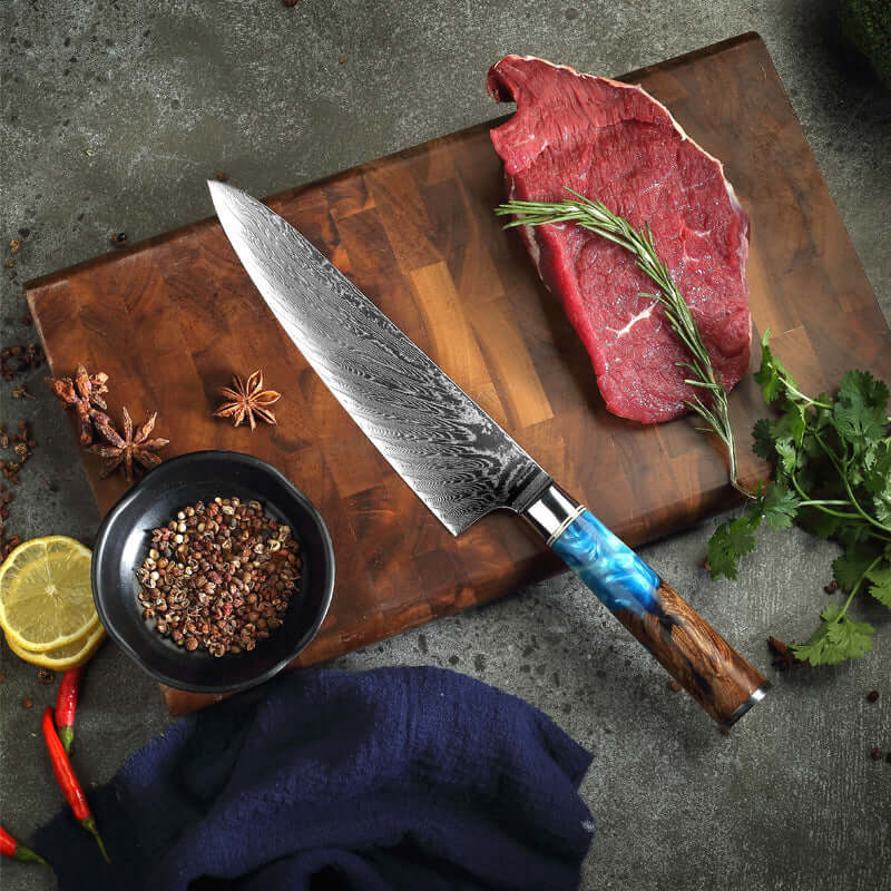 Damascus chef knife with resin handle on wooden cutting board with raw beef, herbs, spices