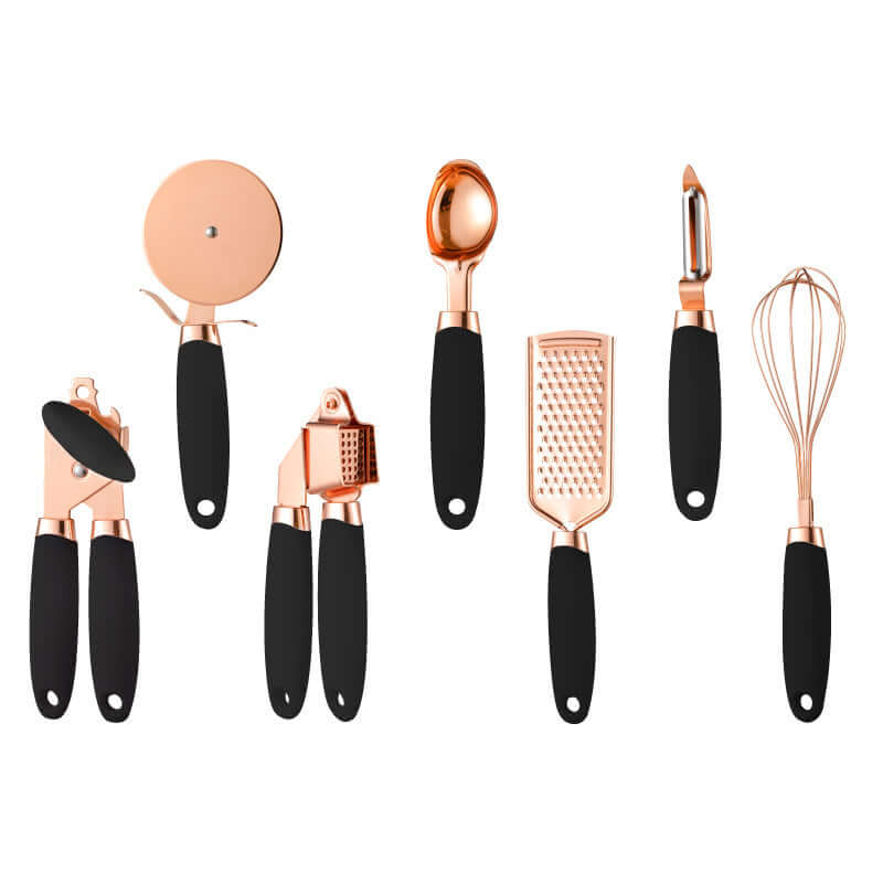 Set of seven rose gold and black kitchen utensils, including pizza cutter, ice cream scoop, can opener, garlic press, grater, peeler, and whisk, arranged on white background.