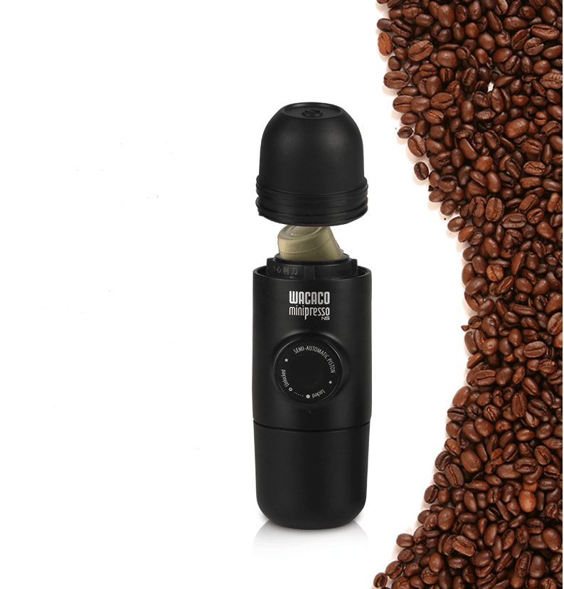 Portable espresso maker beside roasted coffee beans, compact black coffee machine