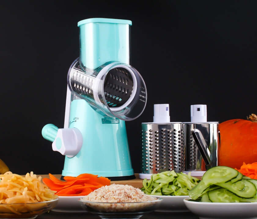 Manual rotary vegetable slicer with grater drums and sliced vegetables on kitchen counter