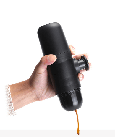 Handheld black manual espresso maker dispensing coffee, portable coffee gadget