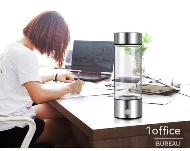 Woman writing at desk with modern glass water bottle and laptop in office setting