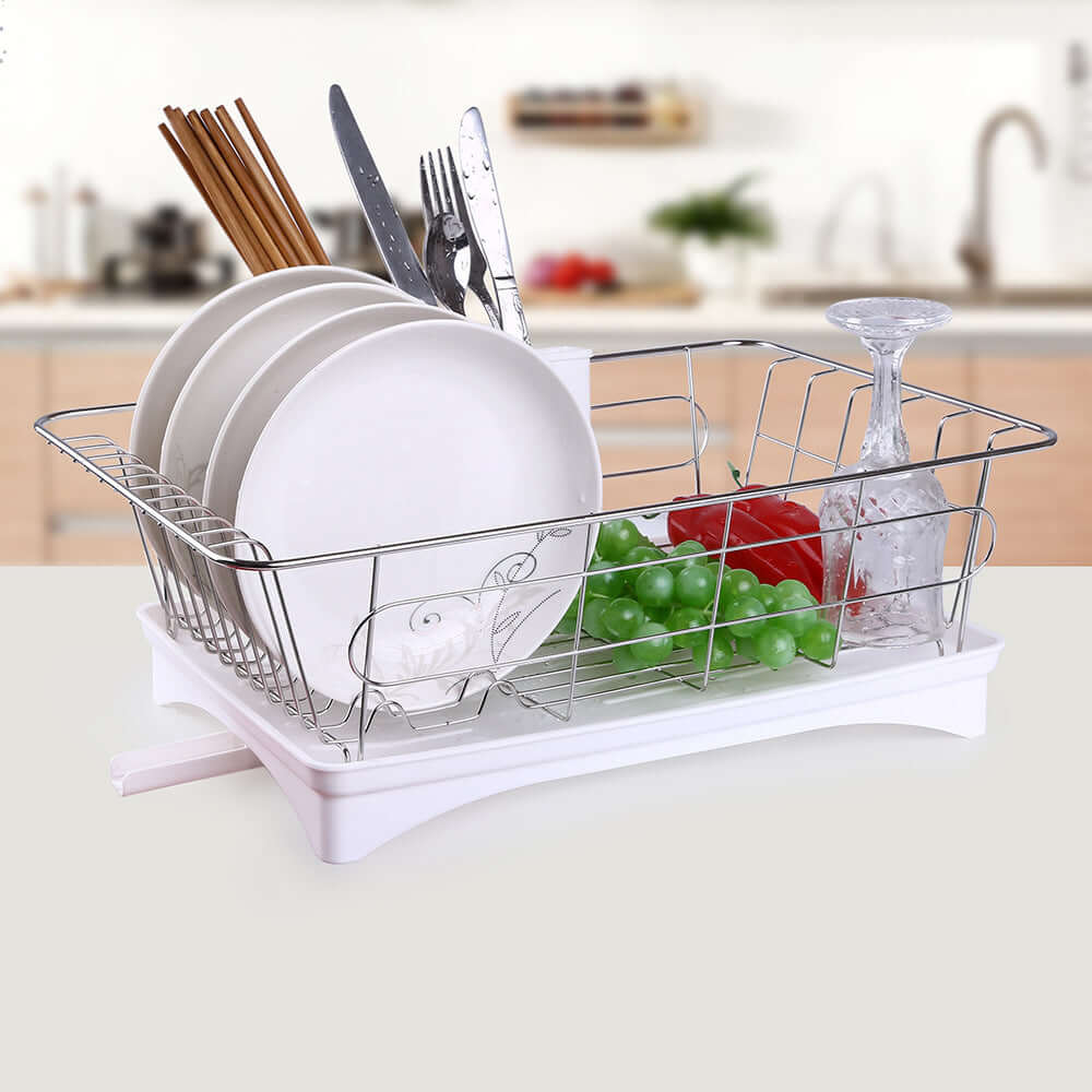 Stainless steel dish drying rack with plates, cutlery, glass, and kitchen accessories on a counter