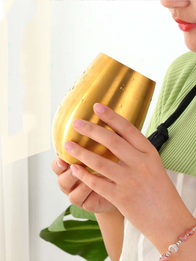 Woman holding a large gold metal drinking cup in kitchen setting