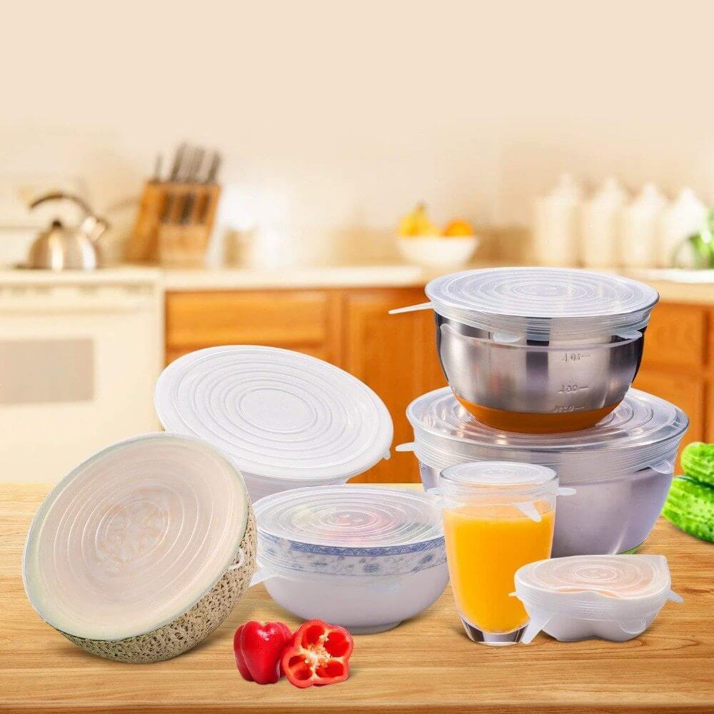 Reusable silicone stretch lids on various kitchen bowls, cups, and containers on a counter