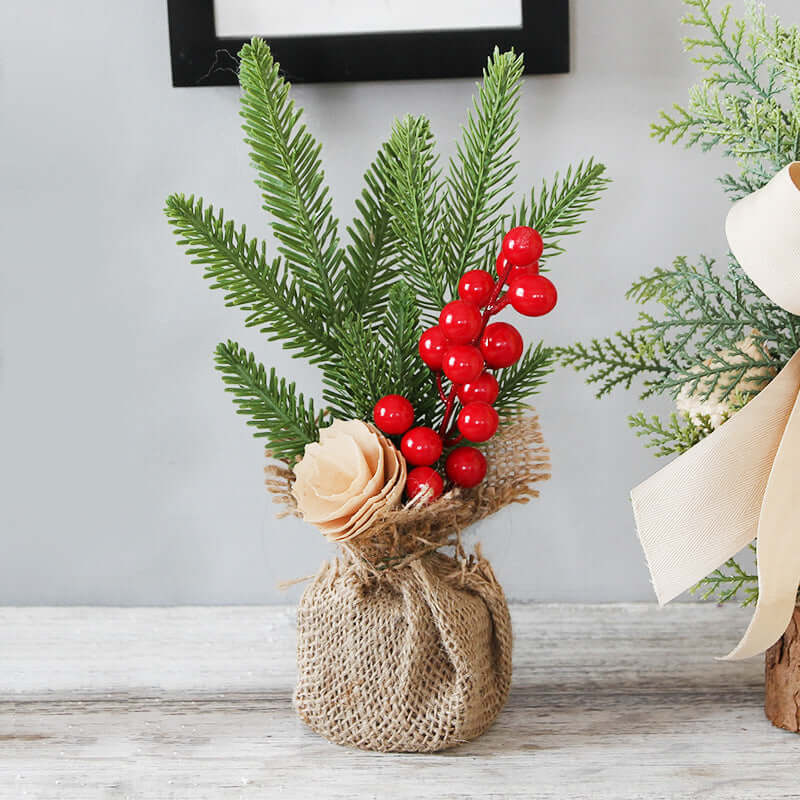 Artificial pine branches with red berries and beige flower in burlap vase for kitchen decor