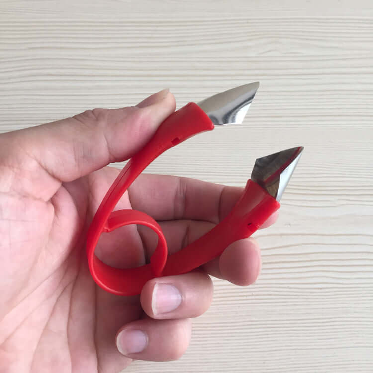 Hand holding a red corn peeler kitchen tool with stainless steel blades