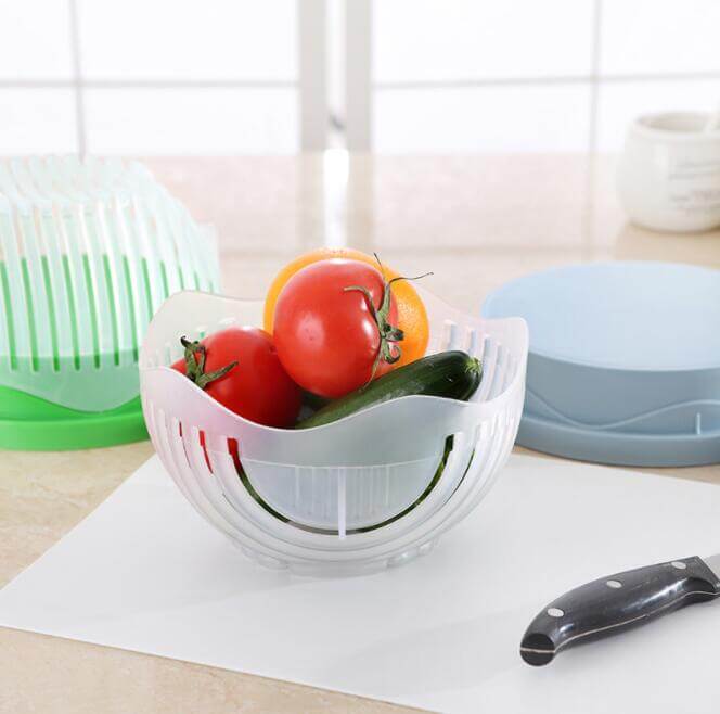 Plastic salad cutter bowl with tomatoes, cucumber, and lemon on kitchen counter