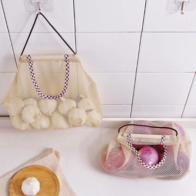 Mesh produce storage bags with garlic and onions on kitchen countertop