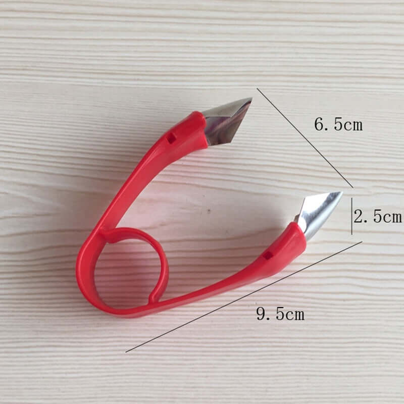 Red kitchen corn cutter tool with stainless steel blades and measurements on light wood background