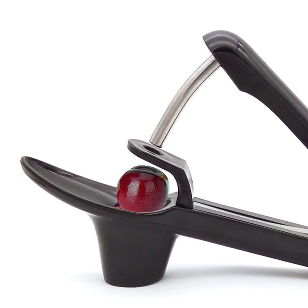 Cherry pitter kitchen tool with a fresh cherry ready for pitting