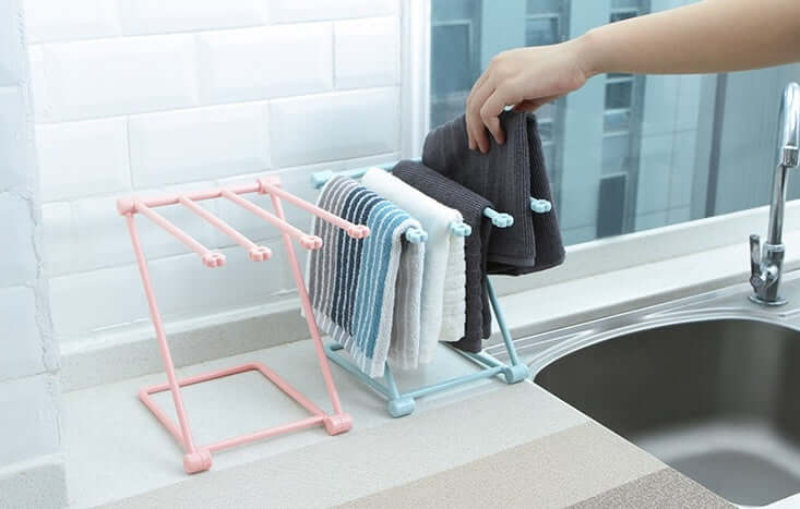 Kitchen countertop towel rack holding multiple dish towels beside a sink and faucet.