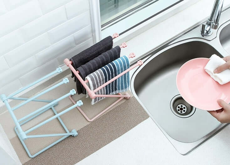 Foldable dish towel racks and hand wiping pink plate beside kitchen sink