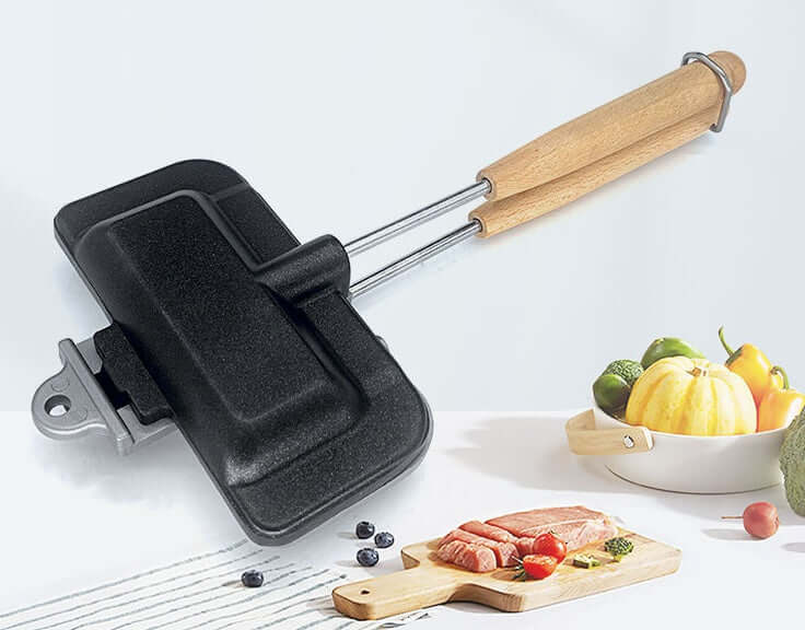 Cast iron sandwich maker with wooden handle, kitchen accessories, cutting board and vegetables
