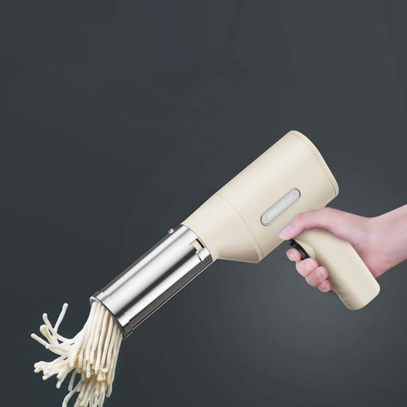 Hand-held electric noodle maker extruding fresh noodles, kitchen gadget on gray background