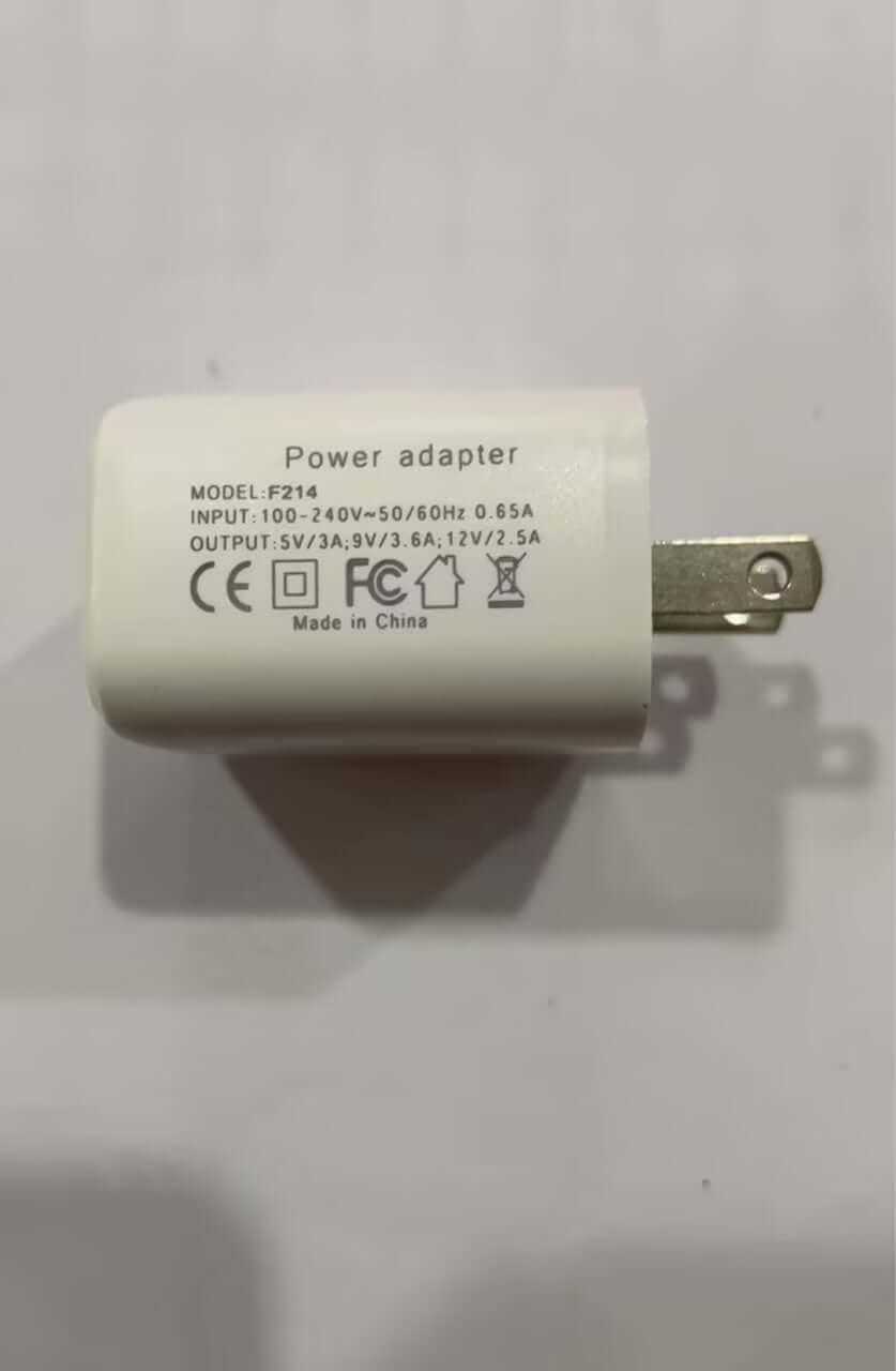 White universal power adapter plug with input output specs and safety certification symbols
