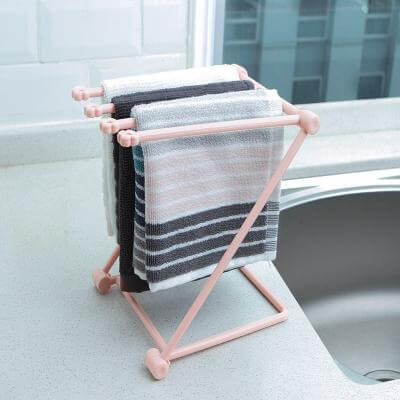 Foldable kitchen towel rack with striped dish towels on countertop by sink