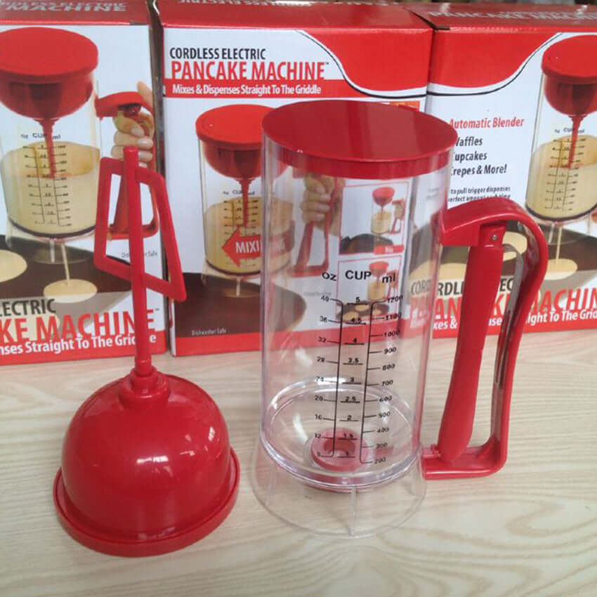 Cordless electric pancake machine with red mixer and clear measuring container on wood table
