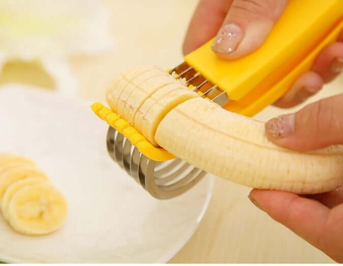 Hand using yellow banana slicer kitchen tool to cut banana into even slices on a plate