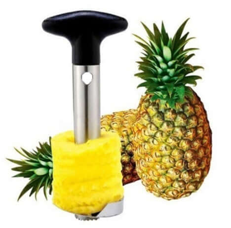 Stainless steel pineapple corer beside whole and peeled pineapples, kitchen tool