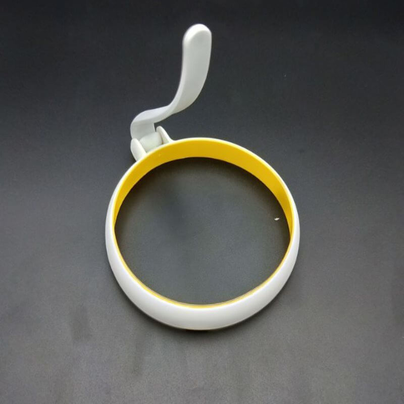 Non-stick egg ring with handle for frying eggs or pancakes on black background