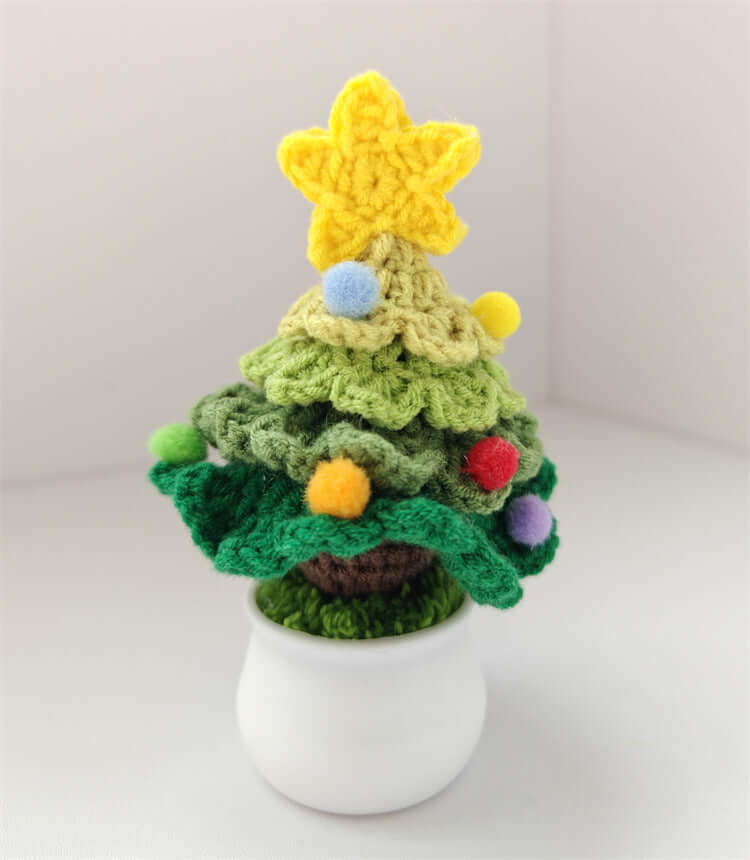 Crocheted mini Christmas tree with star and colorful pom-poms in a white pot