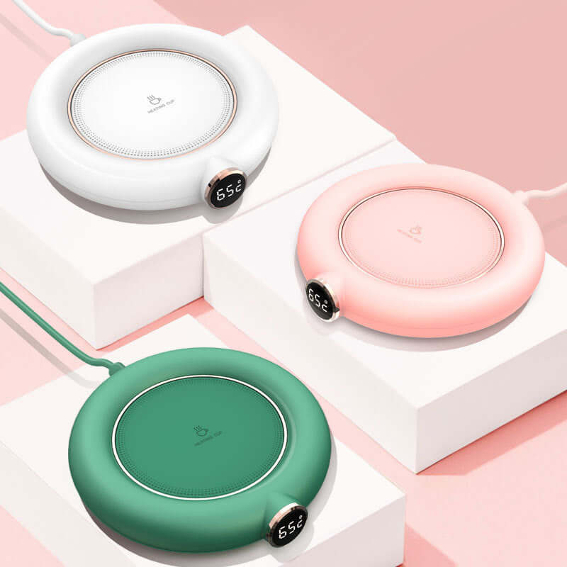 Three round electric mug warmers in white, pink, and green with digital displays.