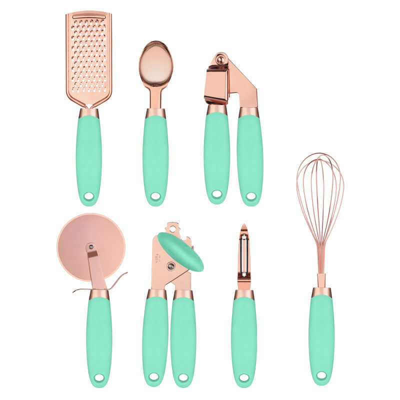 Set of rose gold and mint green kitchen utensils including grater, whisk, peeler, can opener, pizza cutter, spoon, and garlic press on white background.