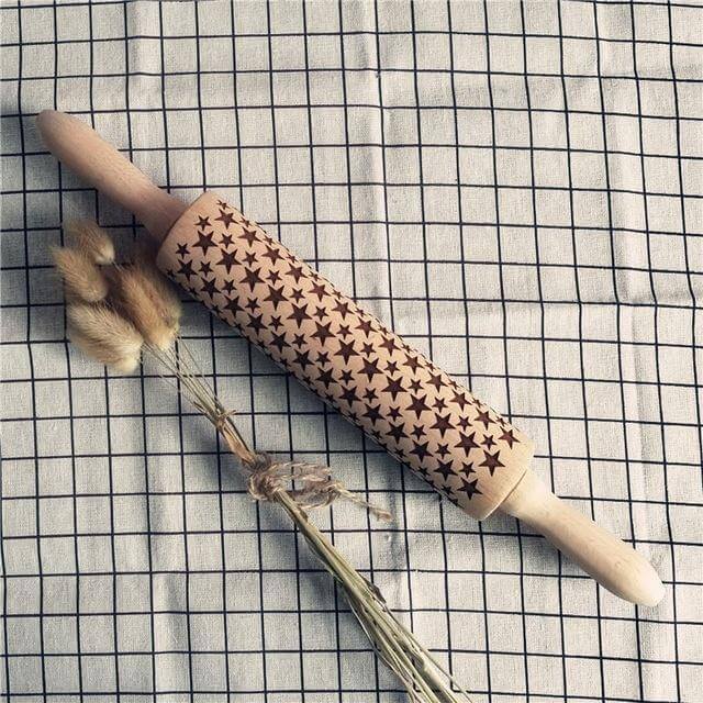 Wooden star-pattern embossed rolling pin on grid kitchen towel with dried wheat
