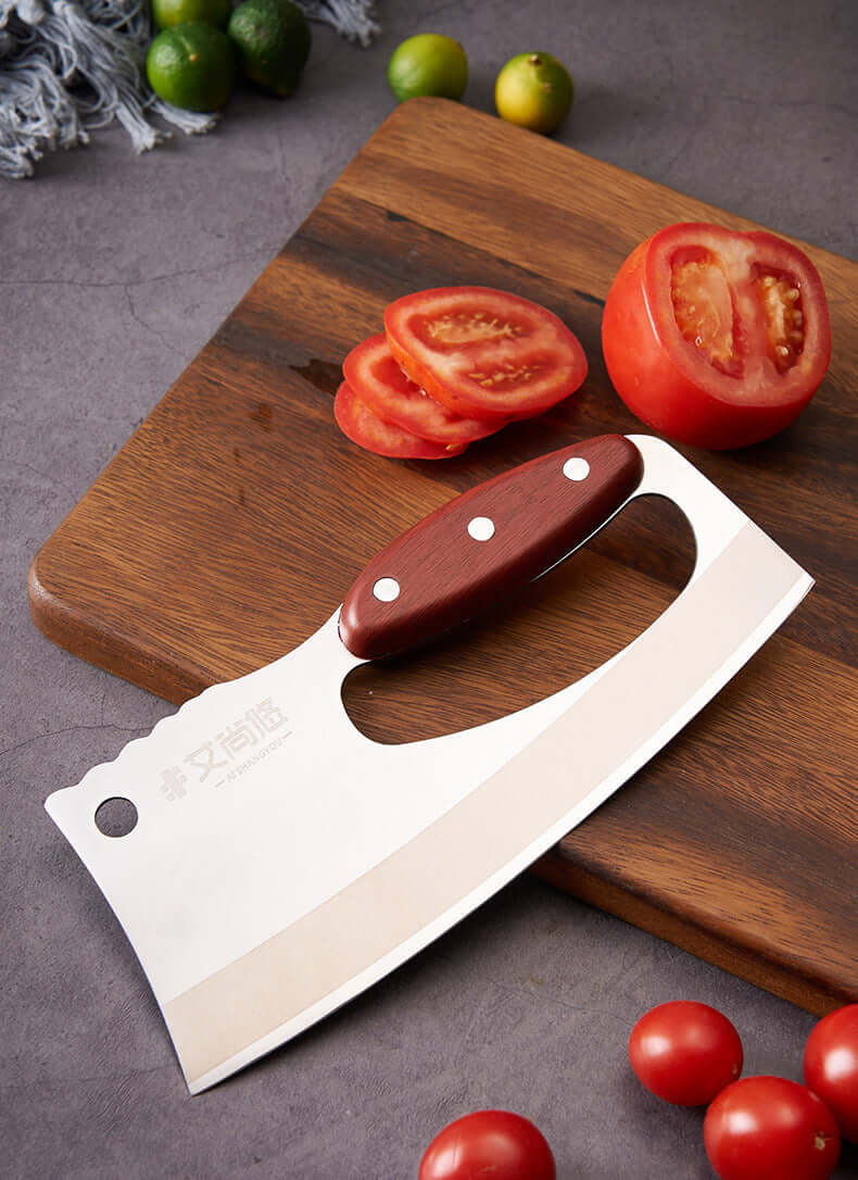 Stainless steel vegetable cleaver with wooden handle on cutting board beside sliced tomato
