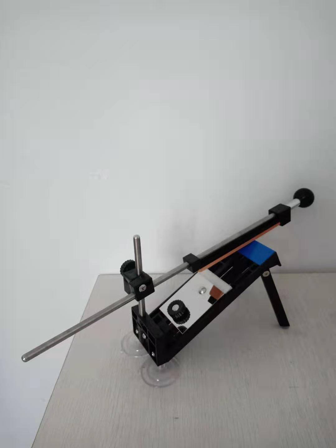 Adjustable kitchen knife sharpening tool with angle guide and suction cups on table