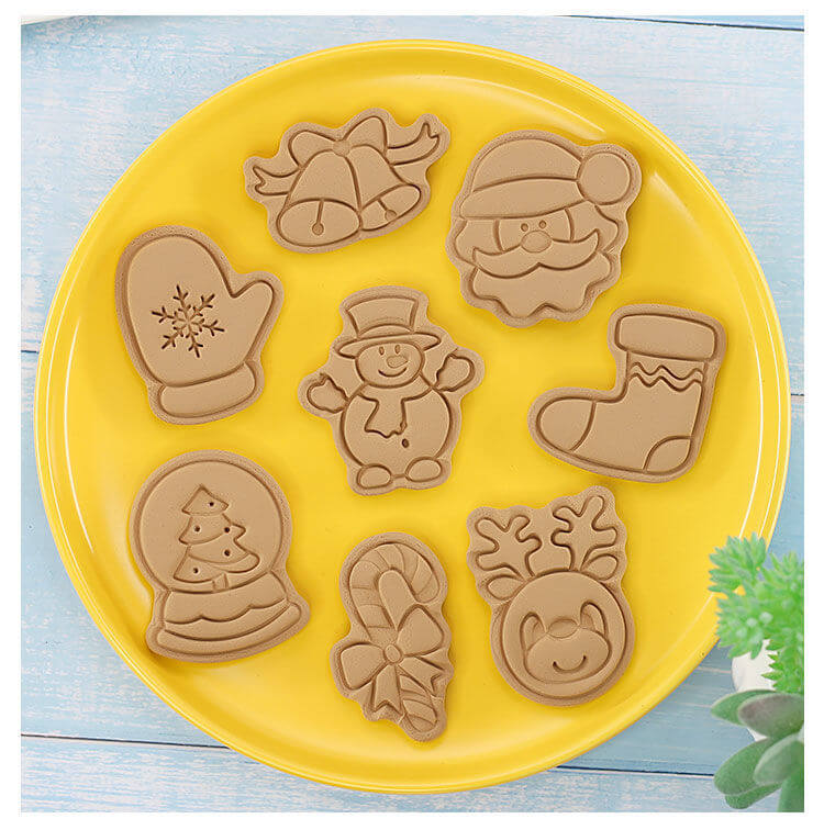 Yellow plate with eight Christmas-themed cookies shaped like Santa, snowman, mitten, and reindeer.