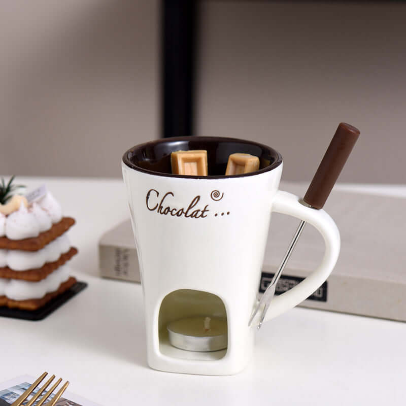 Ceramic chocolate fondue mug set with tealight, dipping fork, and wafers on table