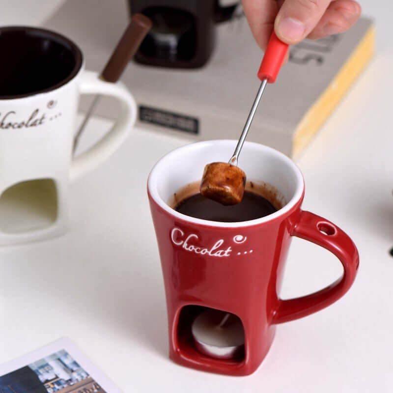 Red ceramic chocolate fondue mug with candle warmer, marshmallow on fondue fork