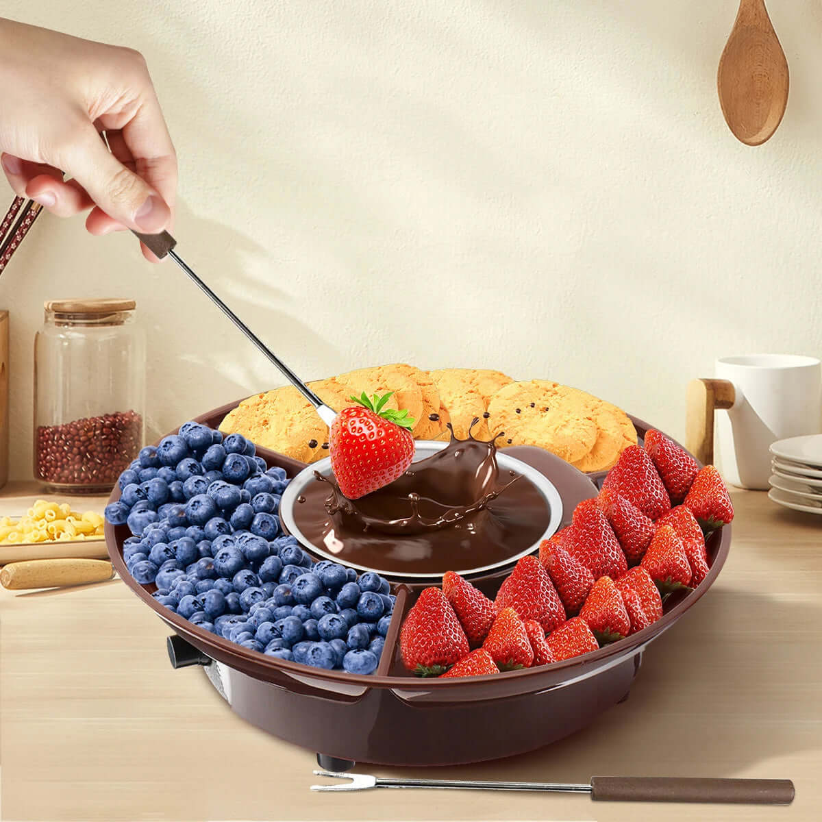 Chocolate fondue set with strawberries, blueberries, cookies, and dipping fork on kitchen table