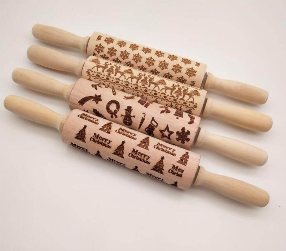 Set of four wooden embossed Christmas rolling pins with festive designs on a white background