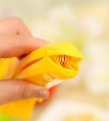 Hand holding yellow kitchen bag clip with metal spring clasp