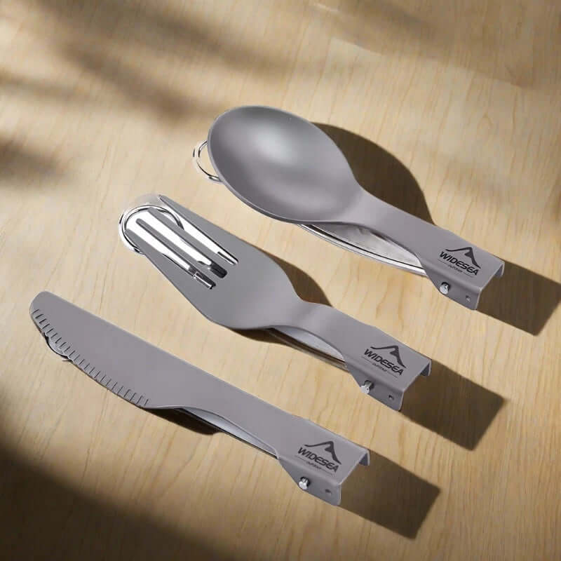 Titanium folding camping utensils set with spoon, fork, and knife on wooden surface